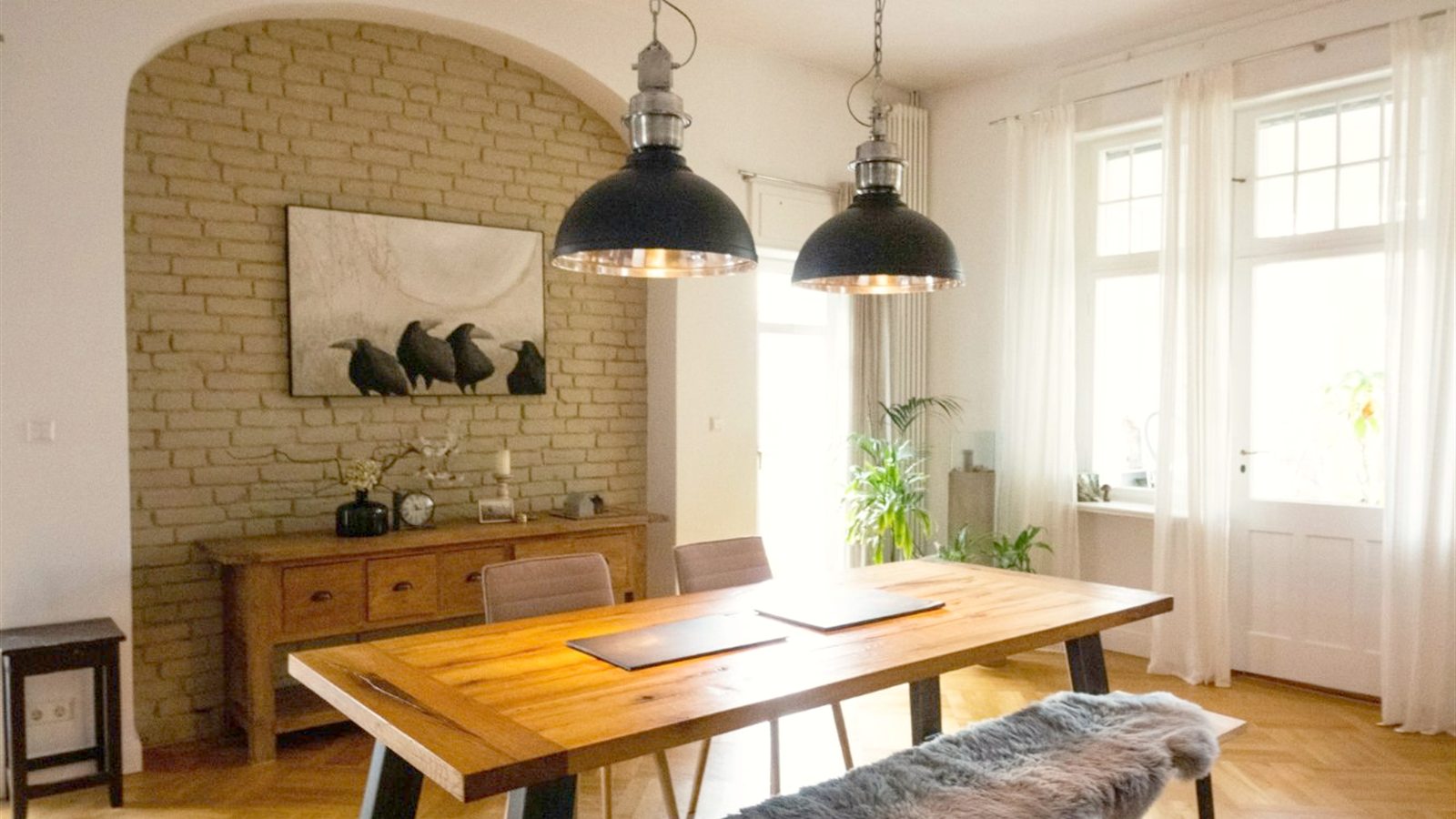 Esszimmer im Altbau mit Holztisch, Industrieleuchten, Backsteinnische und Parkett