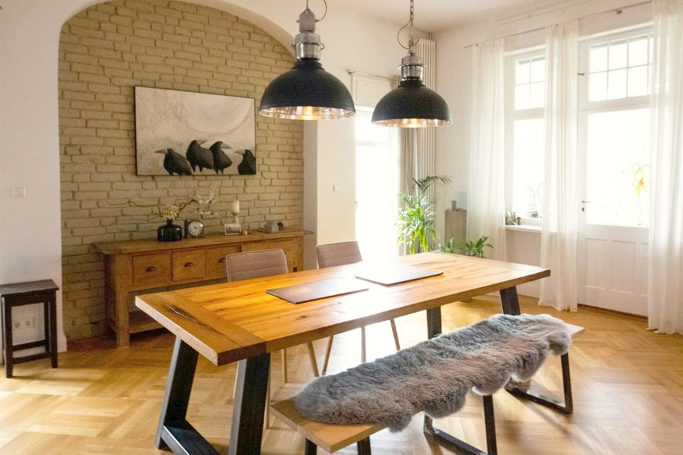 Esszimmer im Altbau mit Holztisch, Industrieleuchten, Backsteinnische und Parkett